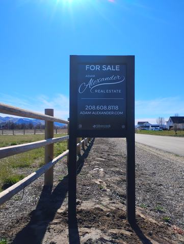 For Sale listing sign on a black two post frame beside a fence